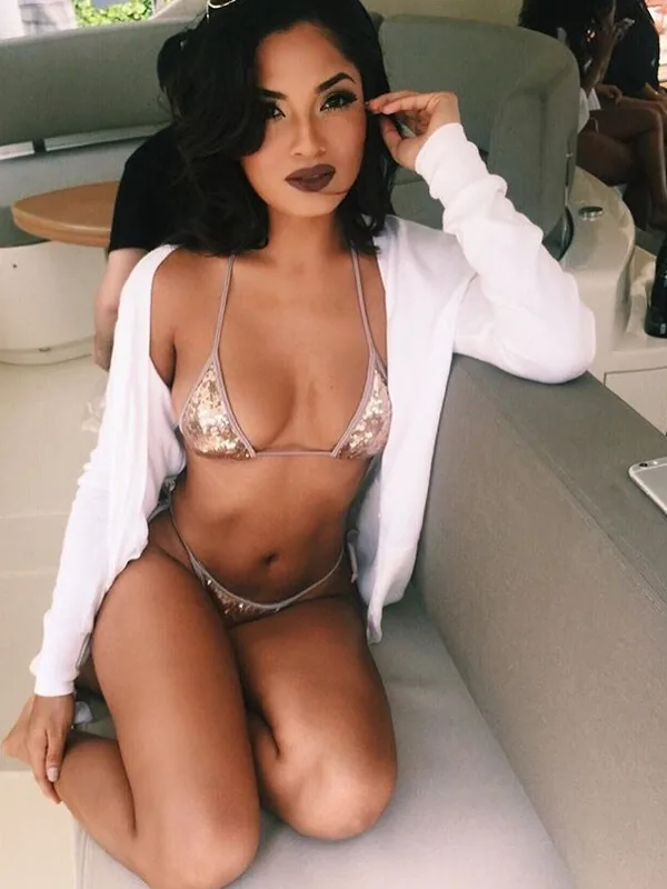 Femme en bikini doré et veste blanche assise sur un canapé de bateau, regardant l'objectif.