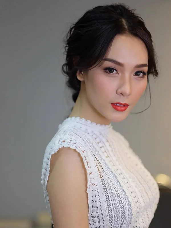 Portrait en buste d'une femme aux cheveux noirs coiffés en chignon, portant un haut blanc en dentelle, regardant l'objectif.
